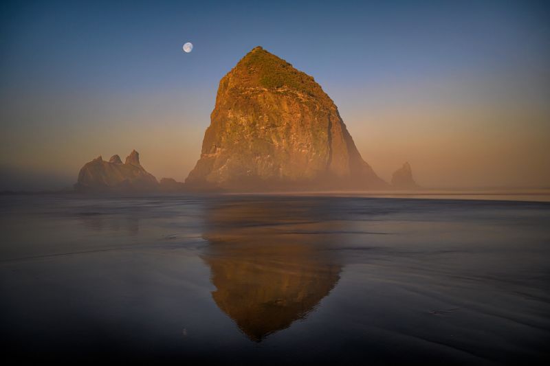 Soubor:Light from the sunrise hits Haystack Rock as the moon sets above on Cannon Beach, Oregon Coast-Flickr.jpg
